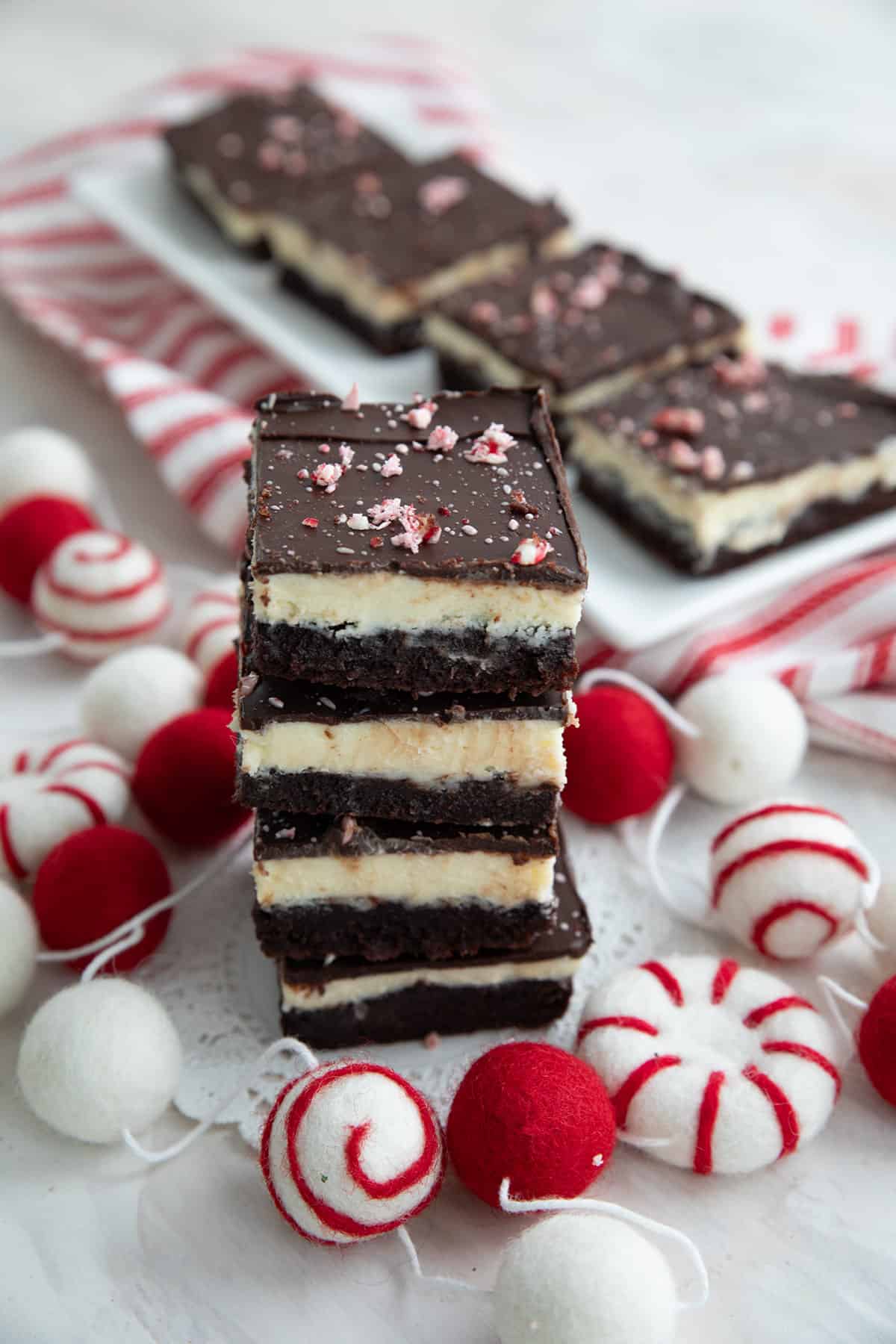 A stack of keto peppermint brownies with red and white decorations around them.