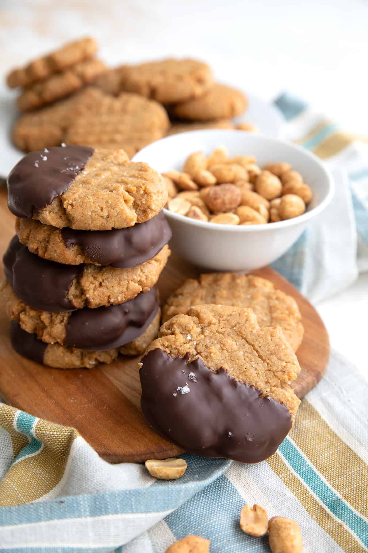Chocolate Dipped Keto Peanut Butter Cookies on a small cutting board over a striped napkin.