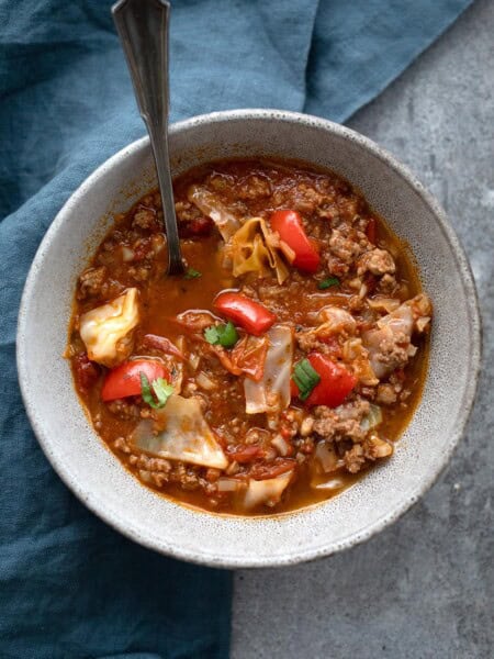 Top down image of Keto Cabbage Soup in a speckled bowl, with a blue napkin underneath.