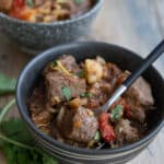 Two bowls of Moroccan Lamb Stew on a weathered wooden table.
