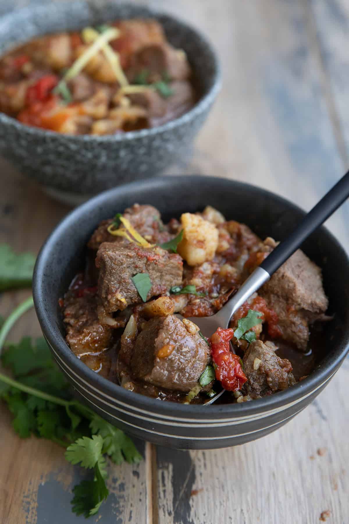 Two bowls of Moroccan Lamb Stew on a weathered wooden table.