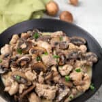 Instant Pot Mushroom Chicken in a black bowl on a weathered grey table.