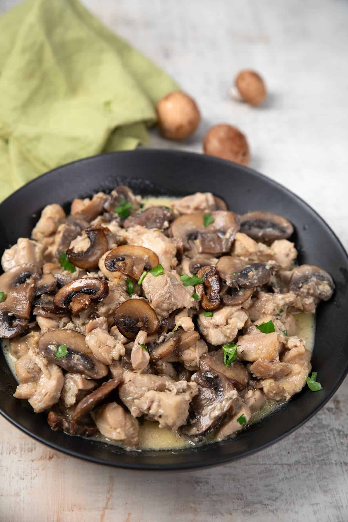 Instant Pot Mushroom Chicken in a black bowl on a weathered grey table.