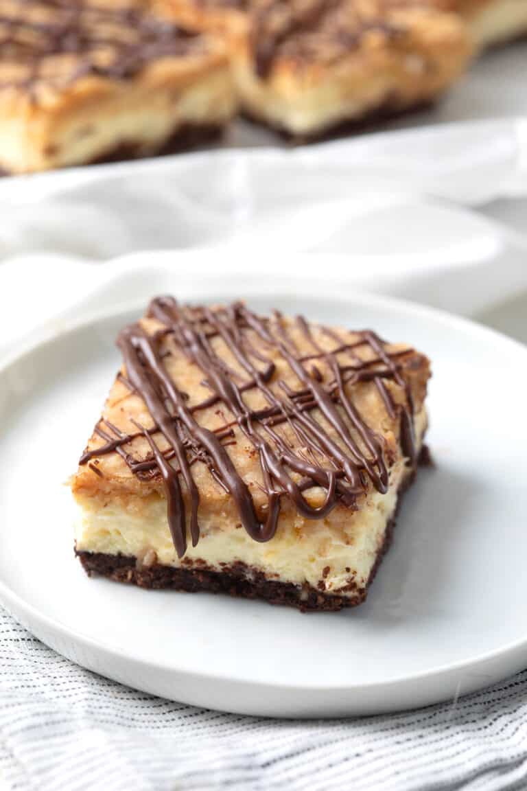 A Keto Samoa cheesecake bar on a white plate over a striped napkin.