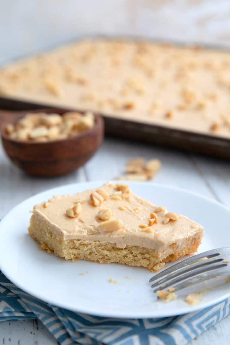 A slice of Keto Peanut Butter Sheet Cake on a white plate with a forkful taken out of it.