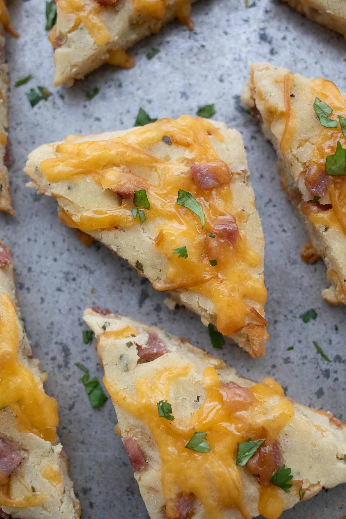 Top down image of ham and cheese scones on a metal baking sheet.