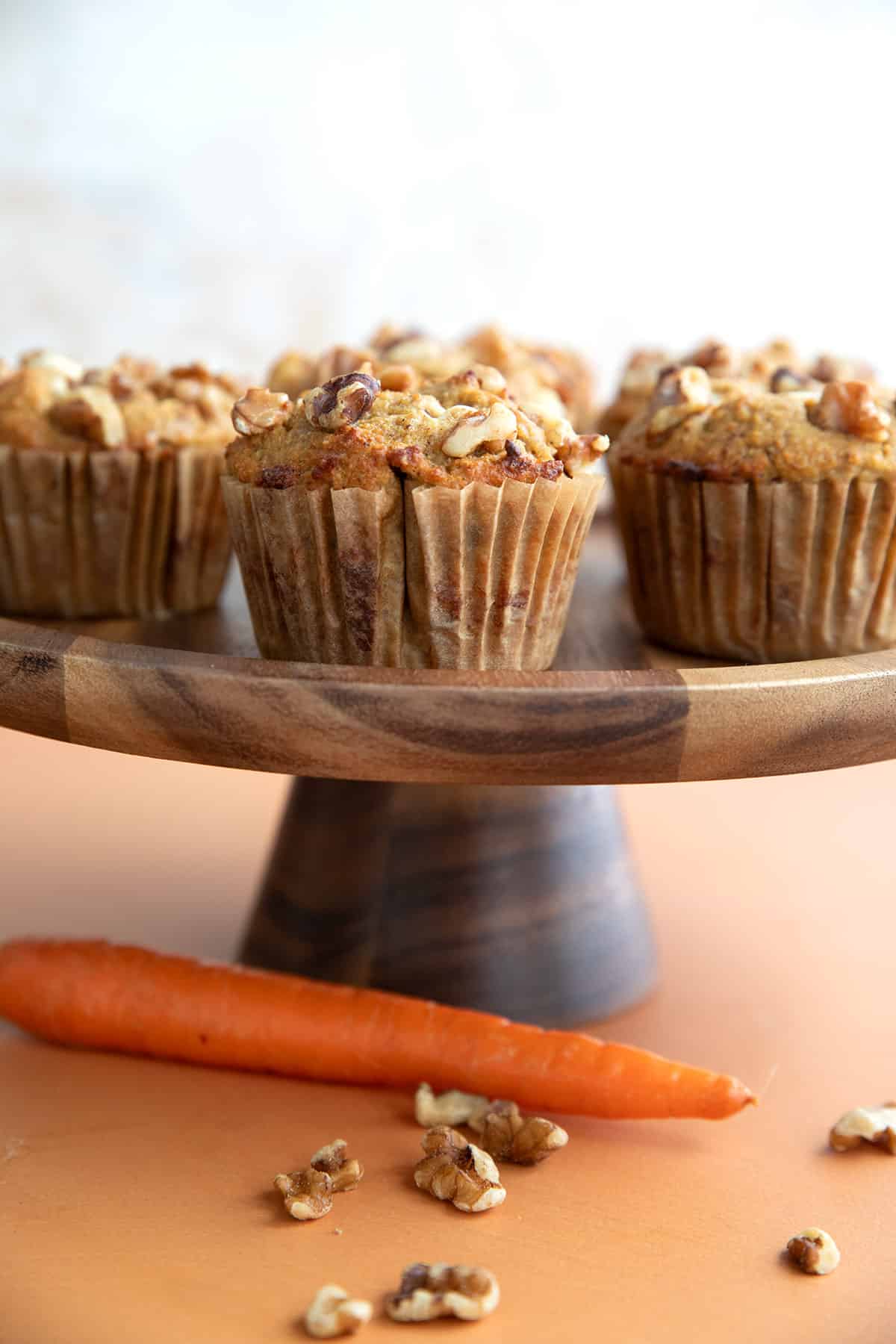 A wooden cake stand filled with freshly baked Keto Carrot Cake Muffins.