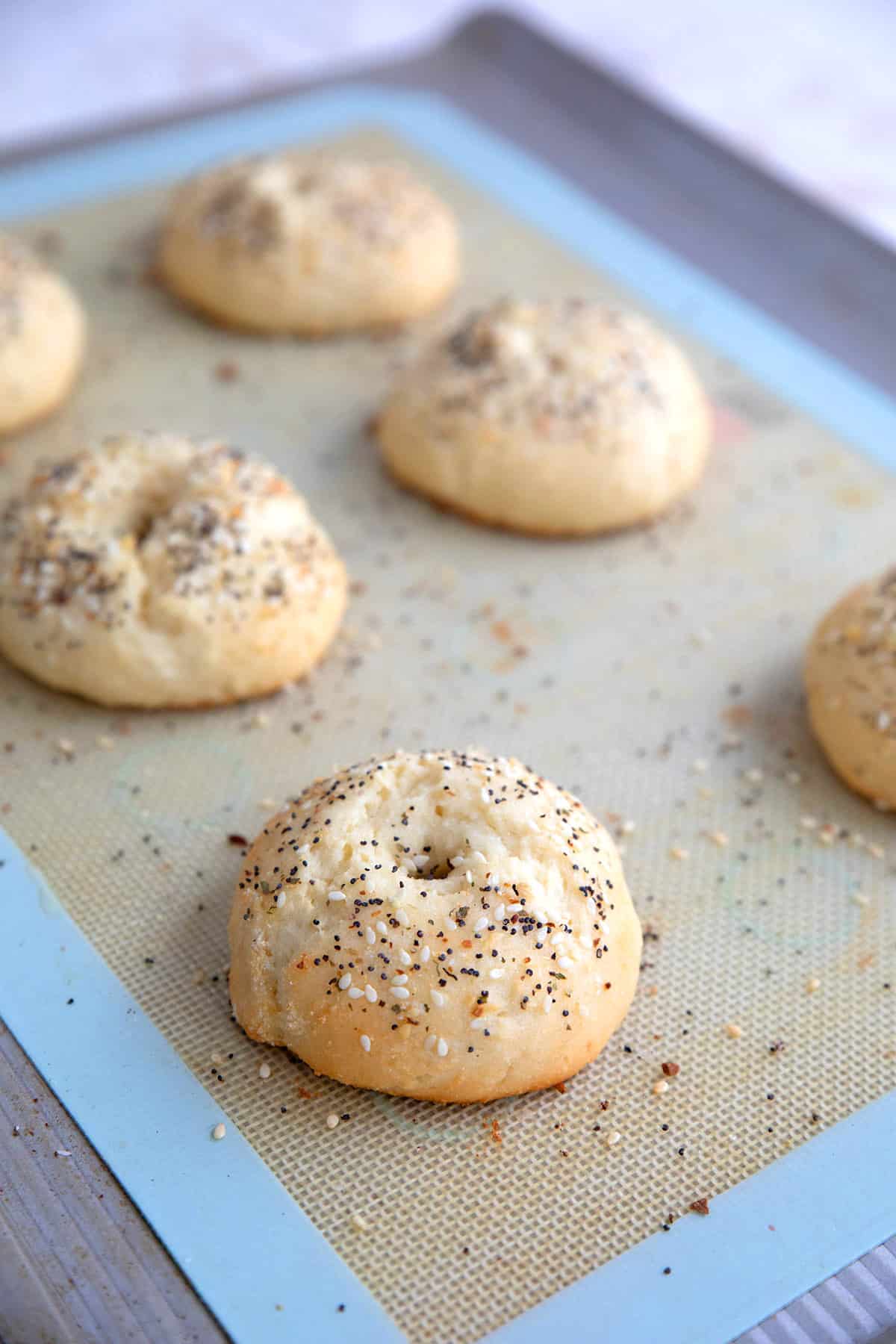 Six high protein bagels on a baking sheet.