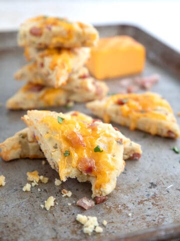 Ham and cheese scones piled up on a metal baking sheet.