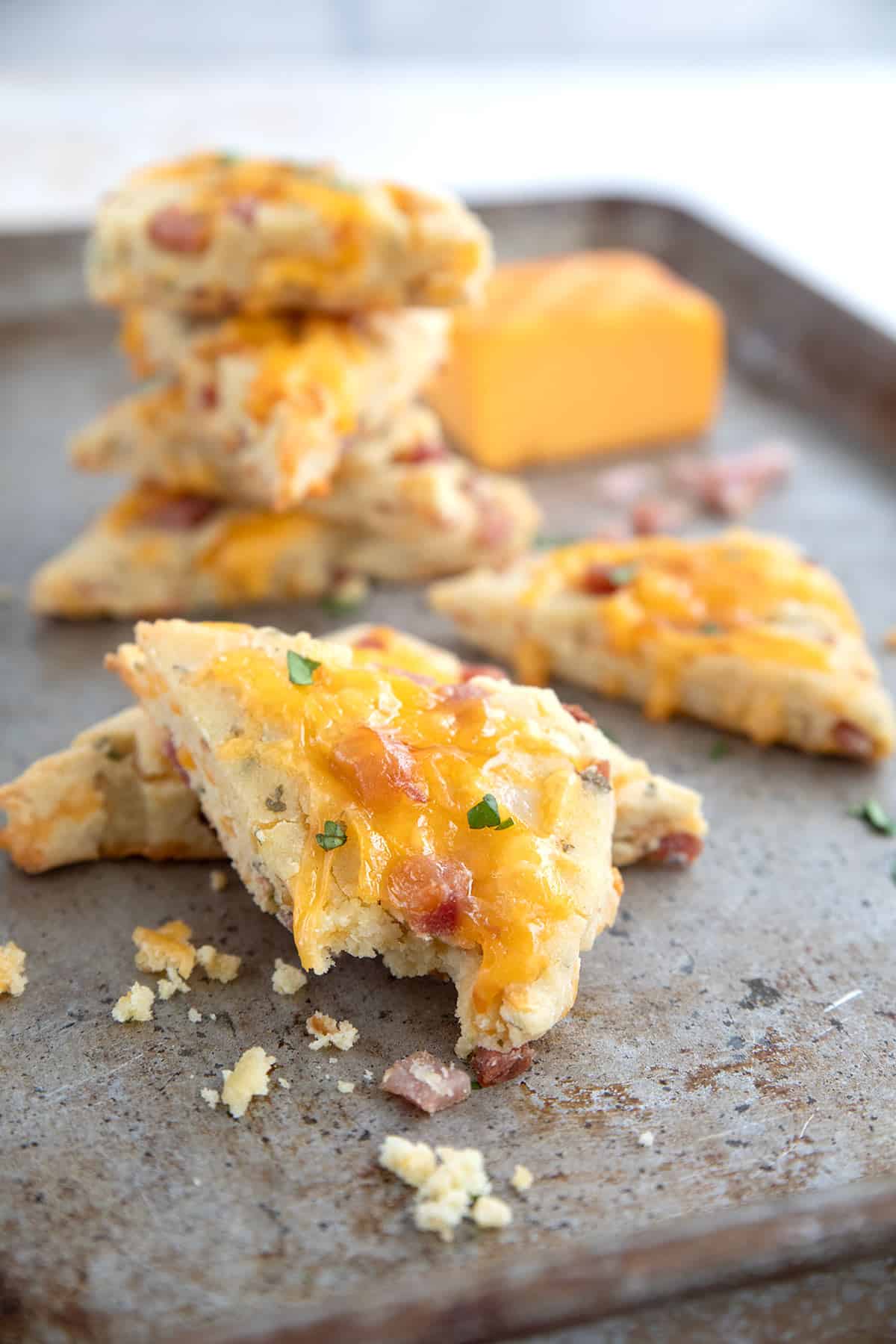 Ham and cheese scones piled up on a metal baking sheet.