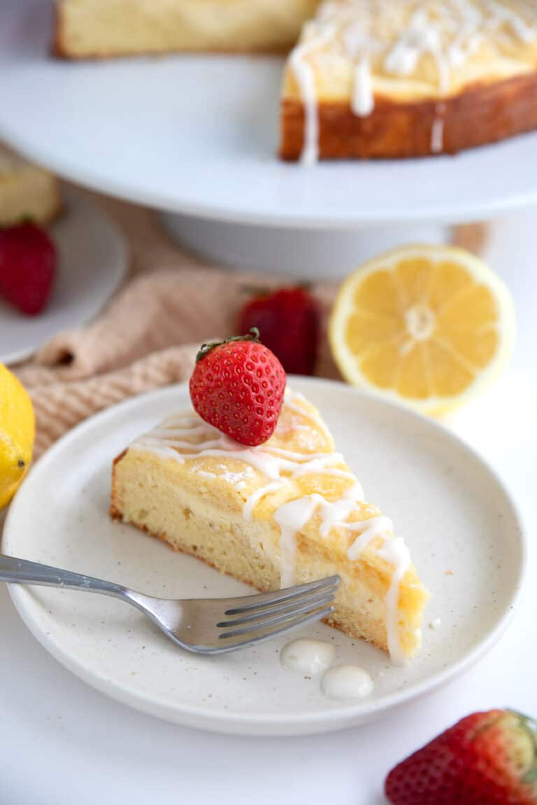 A slice of Keto Lemon Coffee Cake with a ribbon of cream cheese inside and a fresh strawberry on top.