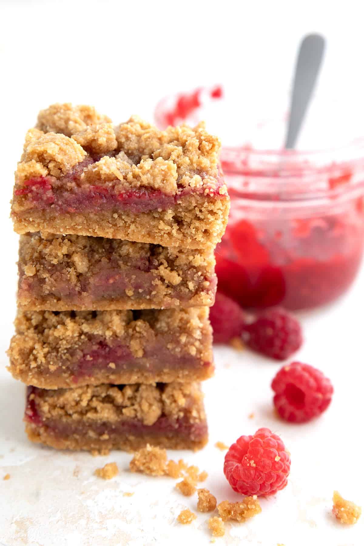 A stack of low carb Peanut Butter and Jelly Bars with a jar of sugar free jam in the background.
