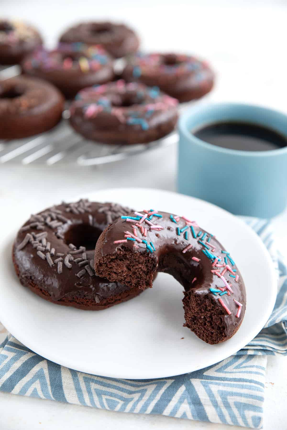 Sugar Free Chocolate Donuts on a white plate with one broken open.