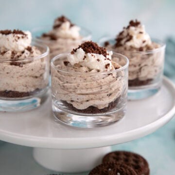 Four desserts cups filled with Keto Cookies and Cream Mousse on a white cake stand.