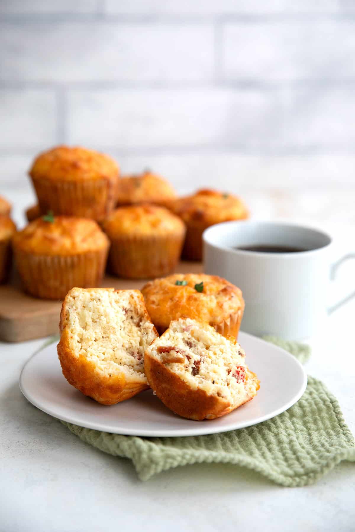 Savory cottage cheese muffins on a white plate over a green napkin, with a cup of coffee in the background.