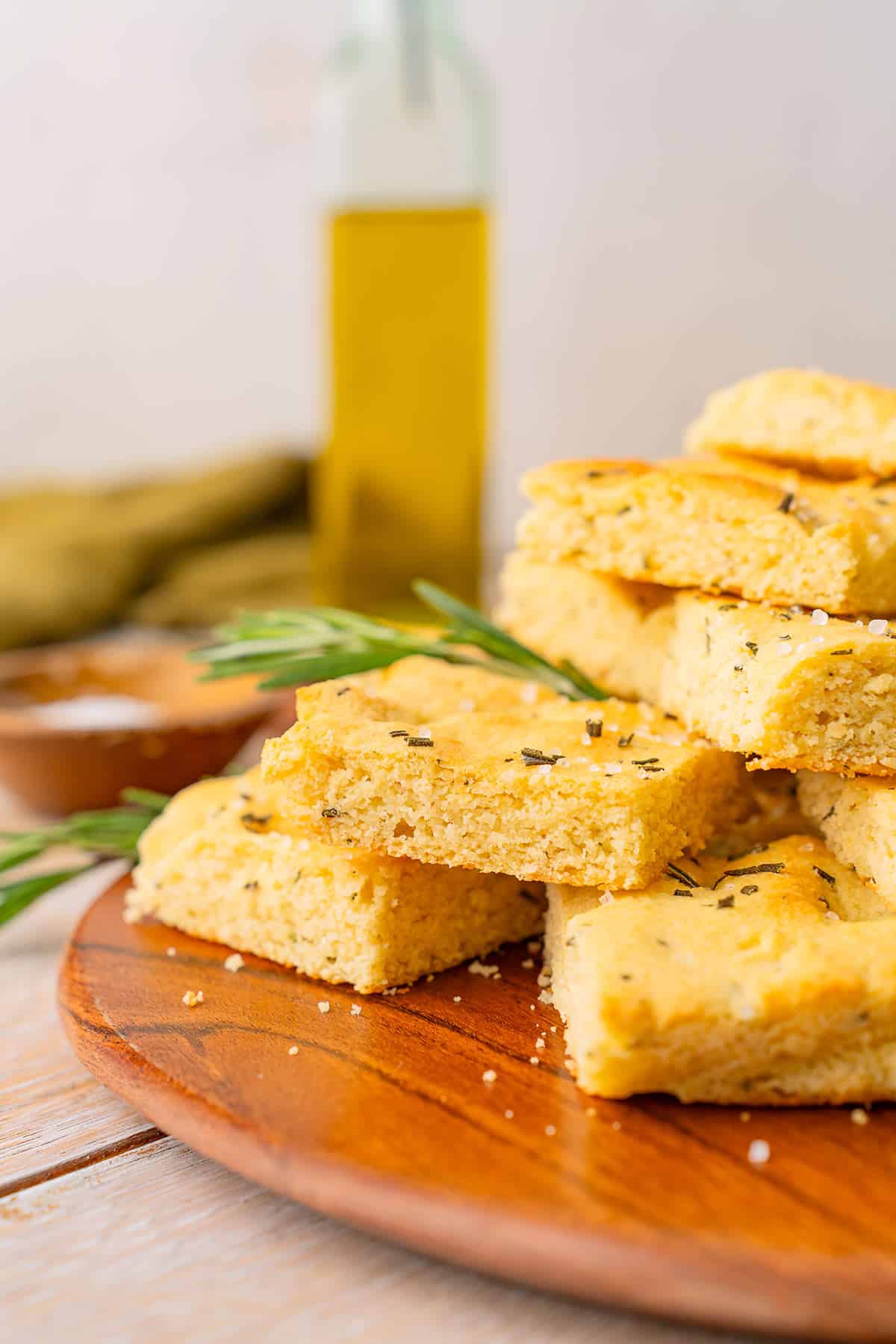 A plate of Keto Focaccia Bread sits in front of a bottle of olive oil.