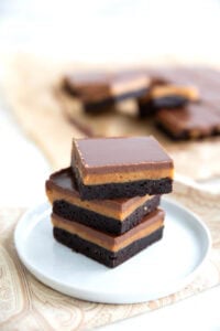 A stack of Keto Peanut Butter Brownies on a white plate over a paisley napkin.