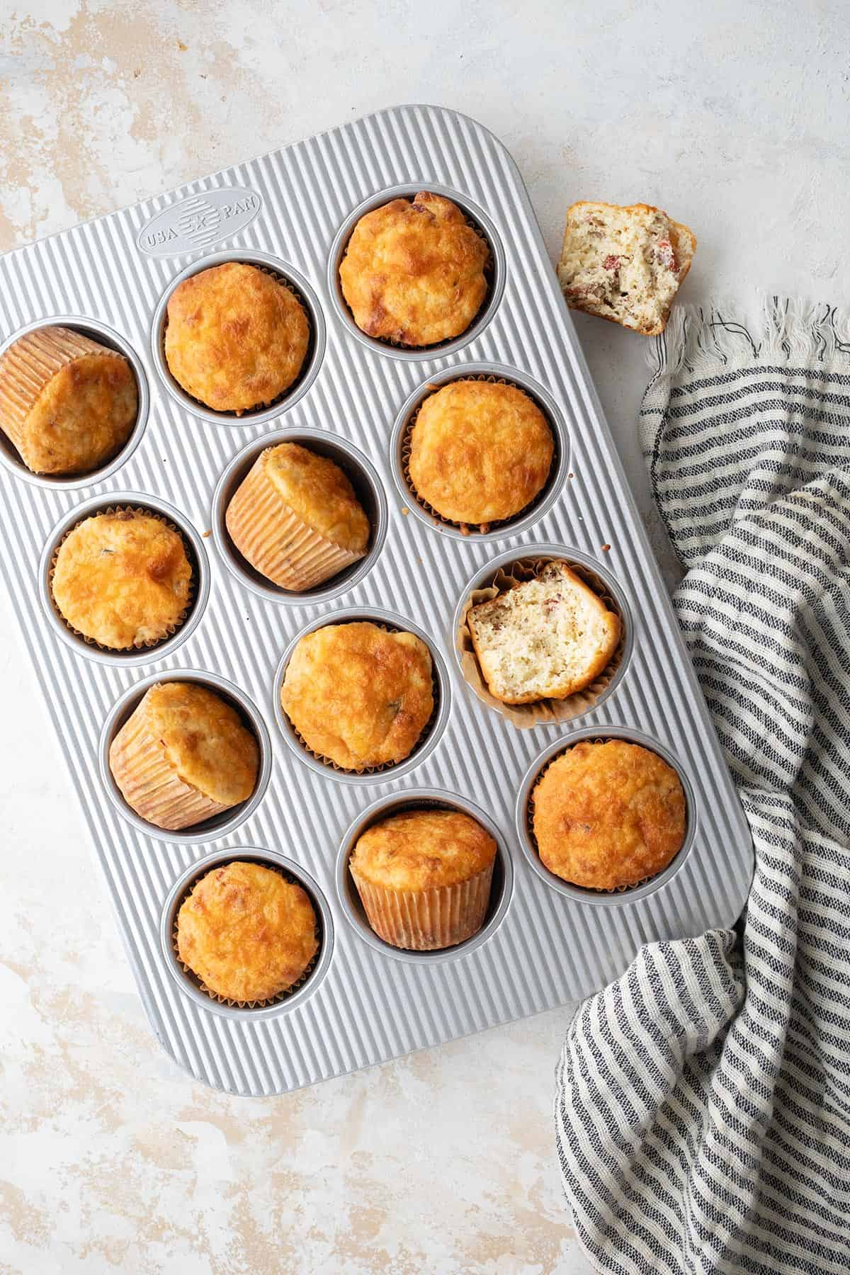 Top down image of savory cottage cheese breakfast muffins in the pan, with one broken open.