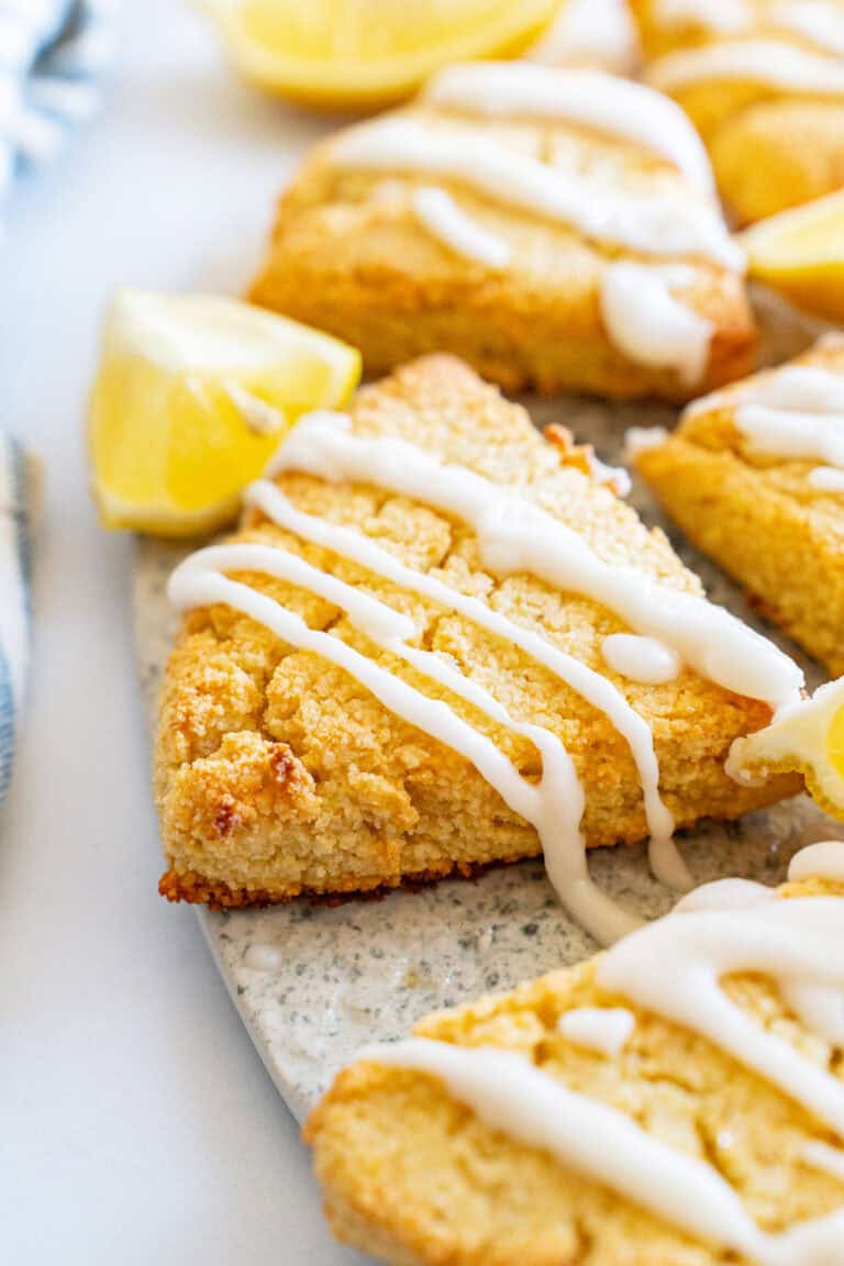 Close up shot of keto lemon scones on a plate with lemon wedges.