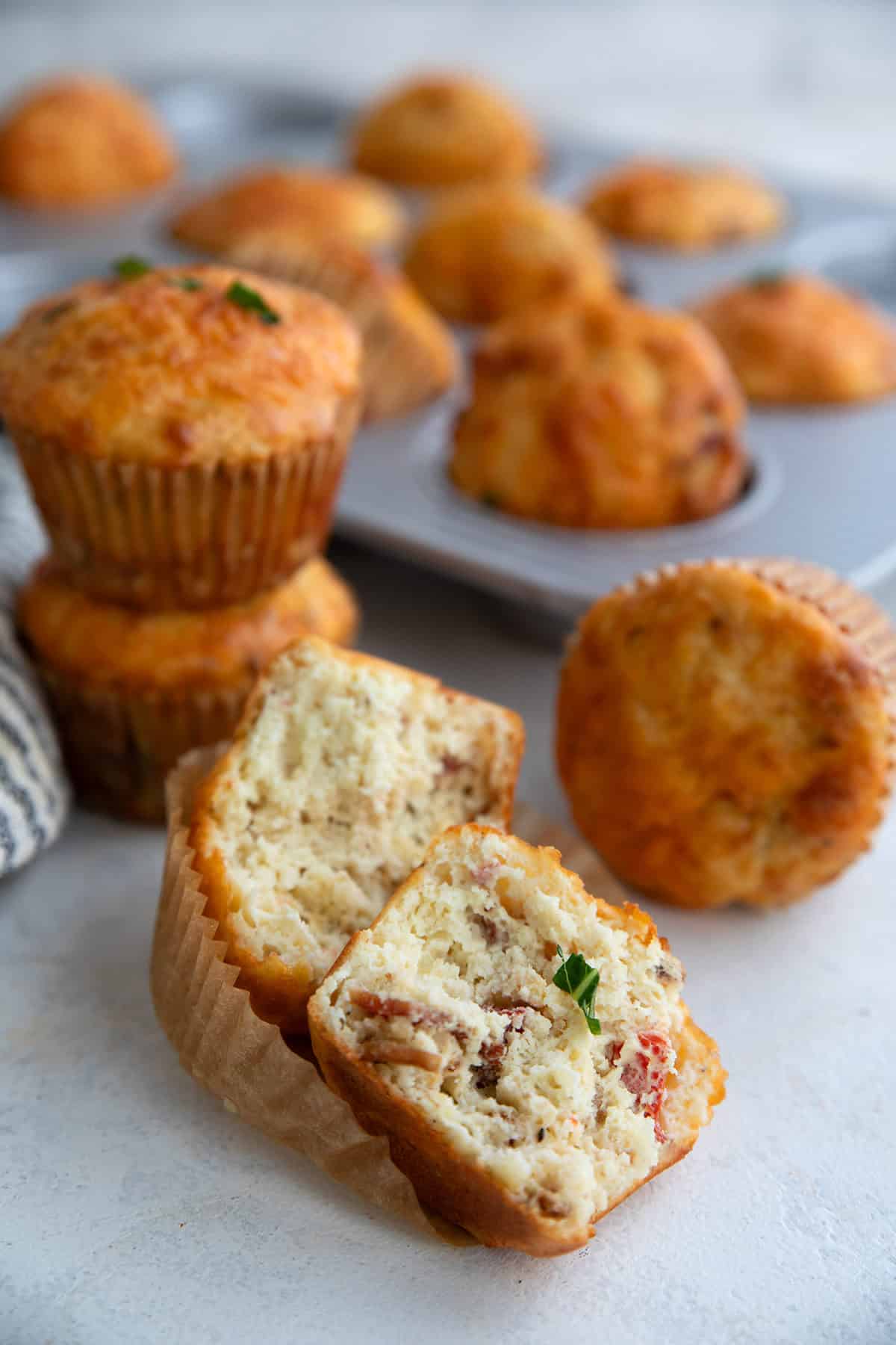 A low carb cottage cheese muffin broken open on a table, with more muffins in the background.