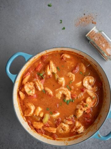 Top down image of Shrimp Creole in a blue dutch oven on a grey table.