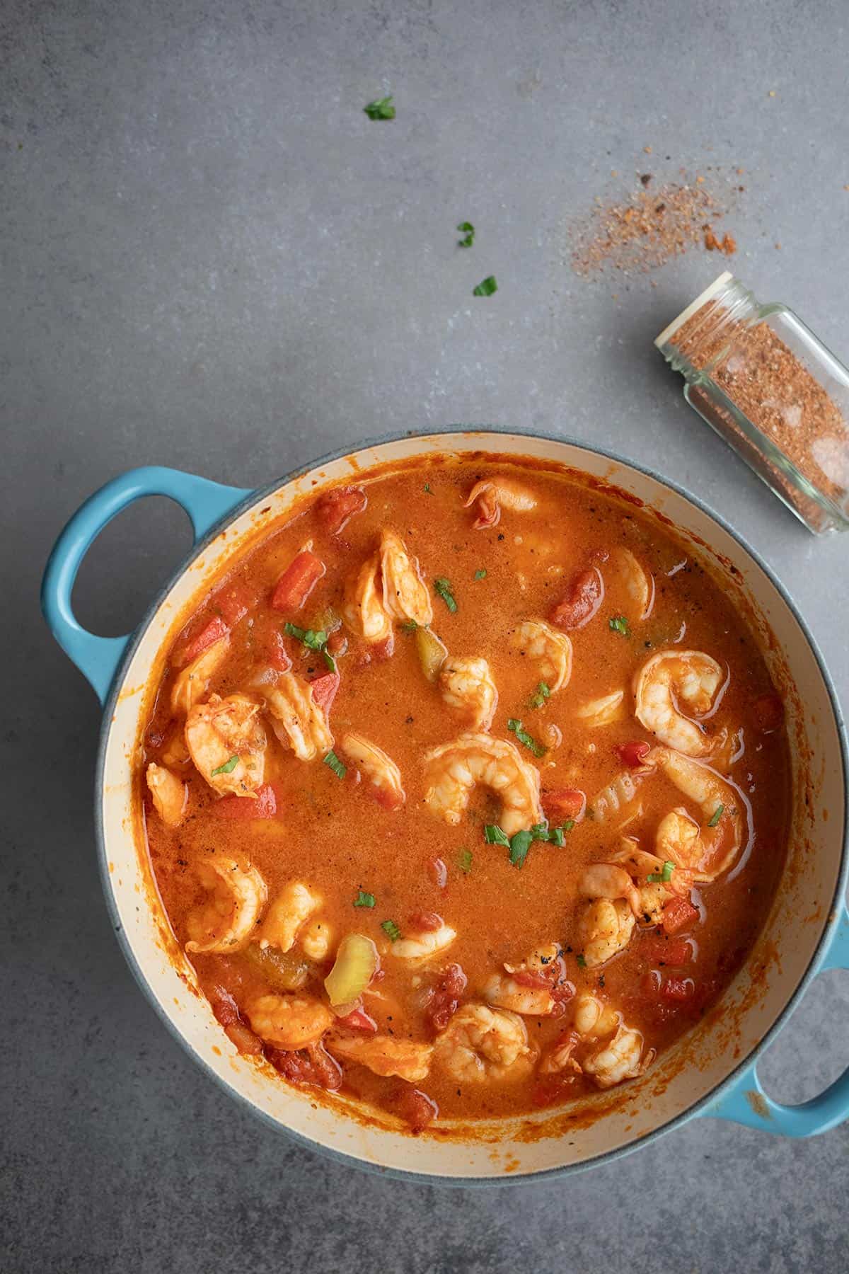 Top down image of Shrimp Creole in a blue dutch oven on a grey table.