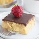 Close up shot of a slice of Keto Boston Cream Poke Cake on a white plate.