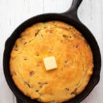 Top down image of keto cornbread in a skillet on a white wooden table.