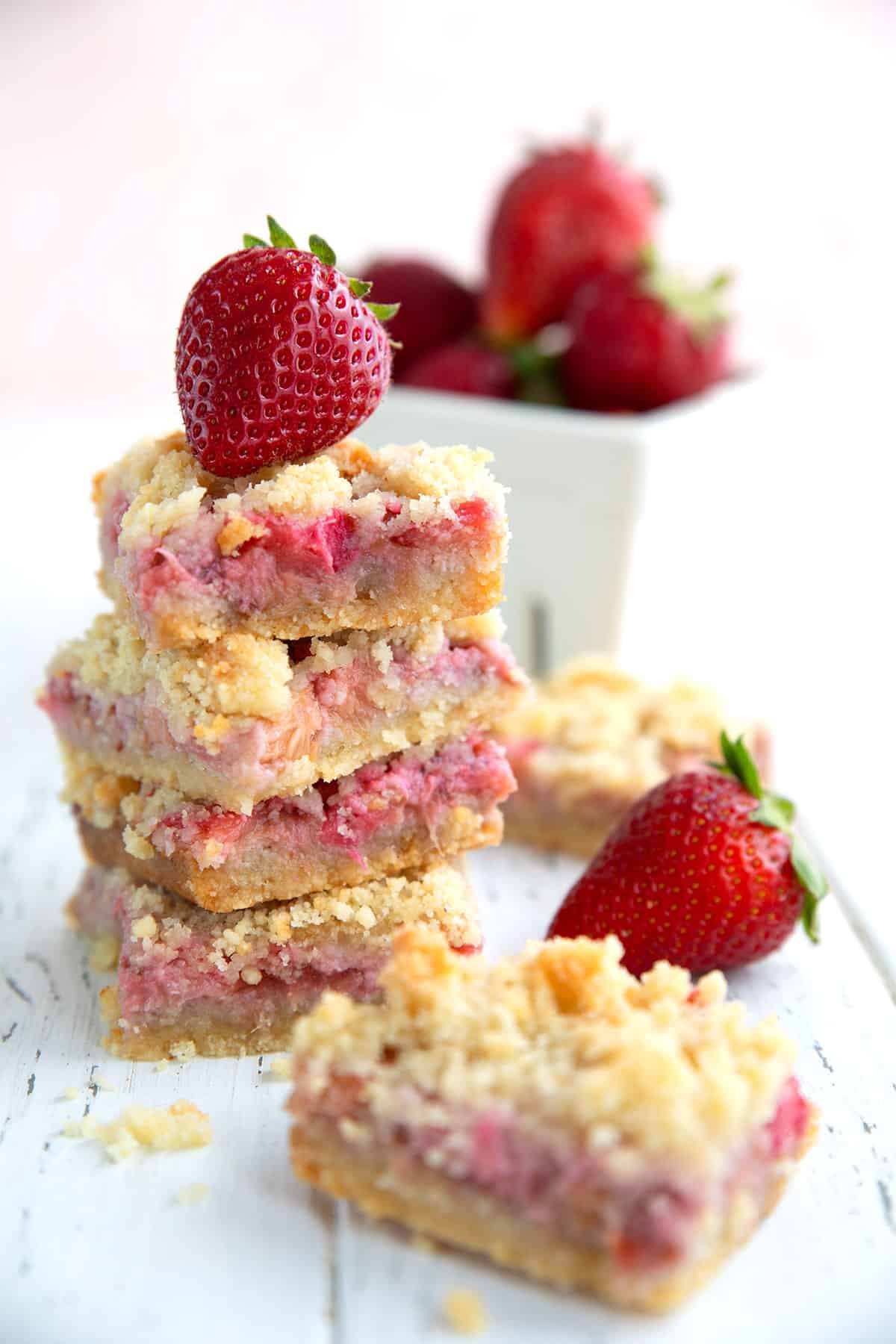 A stack of keto strawberry rhubarb crumb bars with a strawberry on top.
