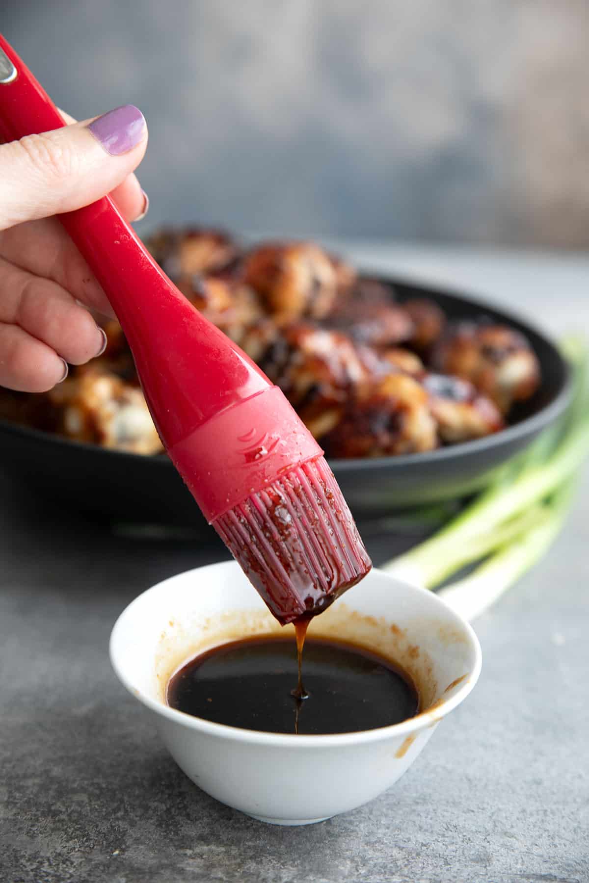 A pastry brush being dipped into a bowl of sugar-free teriyaki sauce.