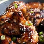 Titled Pinterest image of Keto Teriyaki Wings piled up in a black bowl.