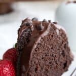 A slice of keto chocolate ricotta bundt cake on a white plate with strawberries.