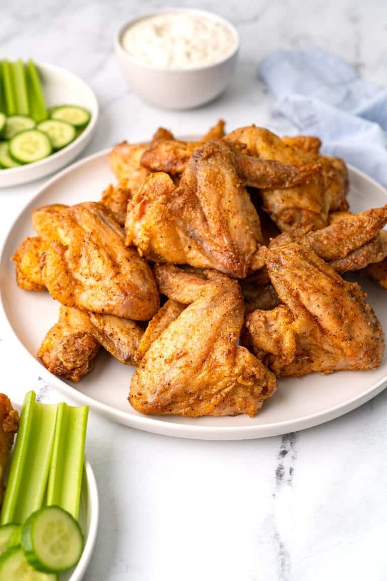 A platter of Old Bay Wings with dipping sauce in a small bowl in the background.