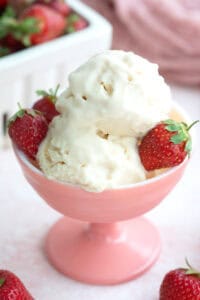 Two scoops of keto ice cream with strawberries in a pink ice cream dish.