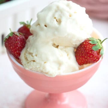 Two scoops of keto ice cream with strawberries in a pink ice cream dish.