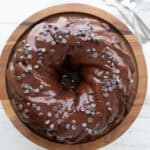 Top down image of Keto Chocolate Ricotta Cake on a wooden cake stand on a white table.