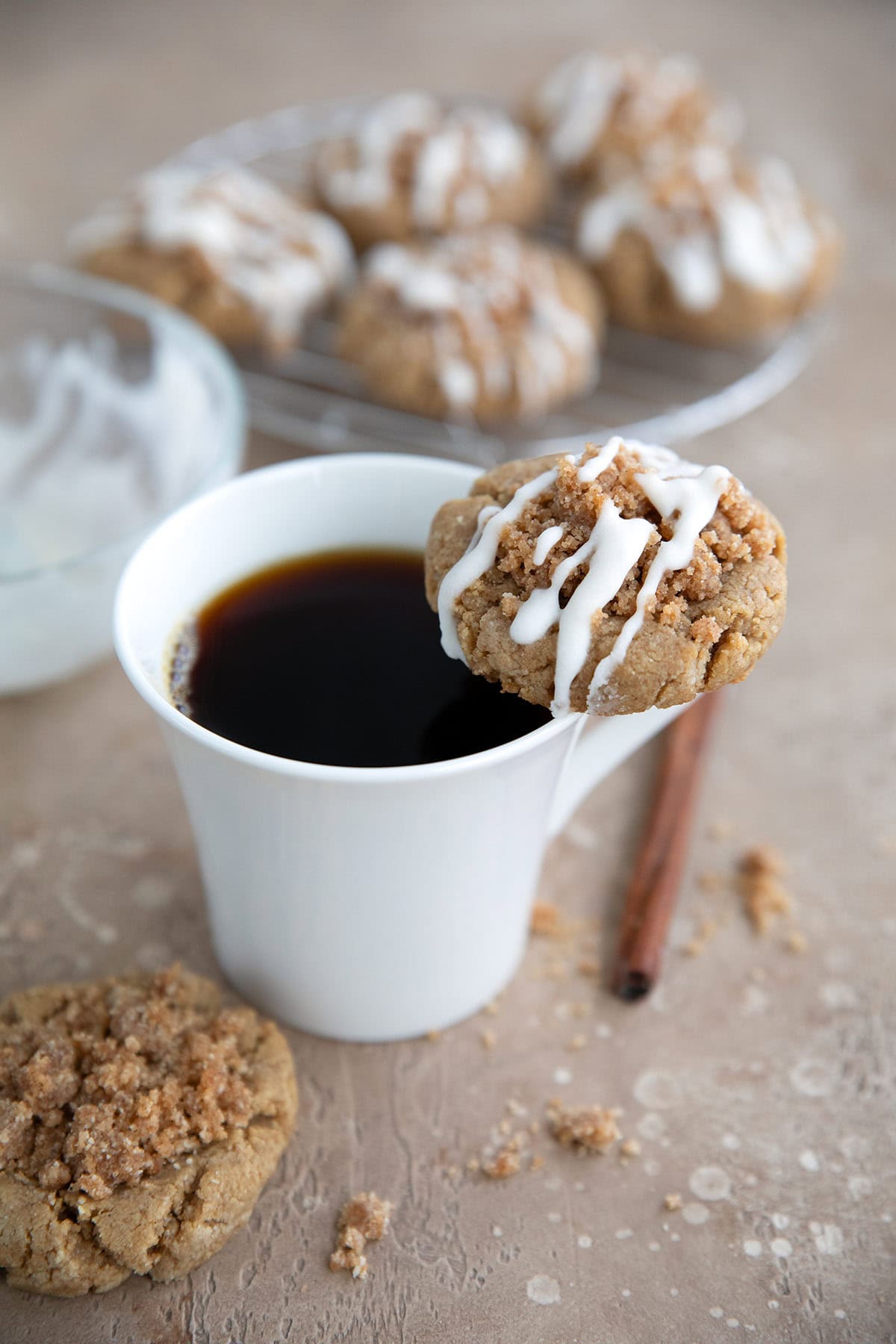 A Keto Coffee Cake Cookie resting on the rim of a white coffee cup.