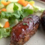 Close up shot of a BBQ Meatloaf Skewer on a plate with salad.