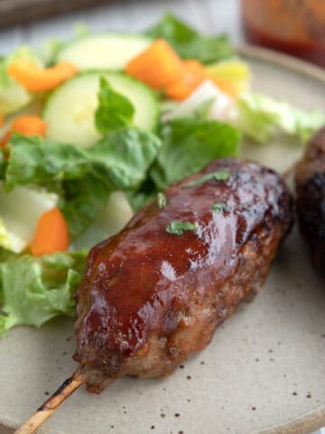 Close up shot of a BBQ Meatloaf Skewer on a plate with salad.