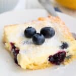 Titled Pinterest image of Keto Blueberry Lemon Gooey Butter Cake on a white plate.