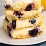 Keto Blueberry Lemon Gooey Butter Cake stacked up on a white plate over a blue napkin.