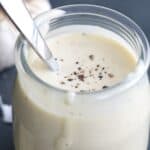 Close up shot of Easy Caesar salad dressing in a jar with cracked pepper on top.