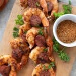 Top down image of Shrimp and Sausage Skewers on a wooden cutting board.