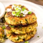 A stack of Keto Zucchini Fritters topped with green onion and feta.