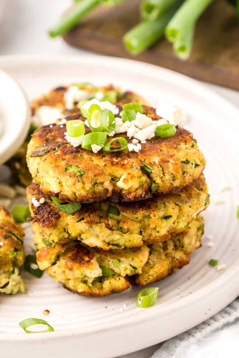 A stack of Keto Zucchini Fritters topped with green onion and feta.