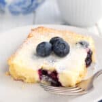 A slice of Keto Blueberry Lemon Gooey Butter Cake on a white plate with a fork.