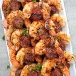 Cajun shrimp and sausage laid out on a white platter.