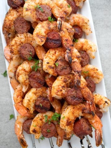 Cajun shrimp and sausage laid out on a white platter.