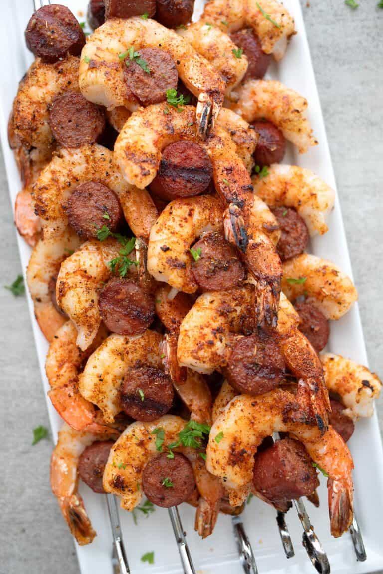 Cajun shrimp and sausage laid out on a white platter.