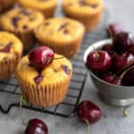 Keto Cherry Chocolate Chip Muffins on a wire baking rack with a bowl of fresh cherries.